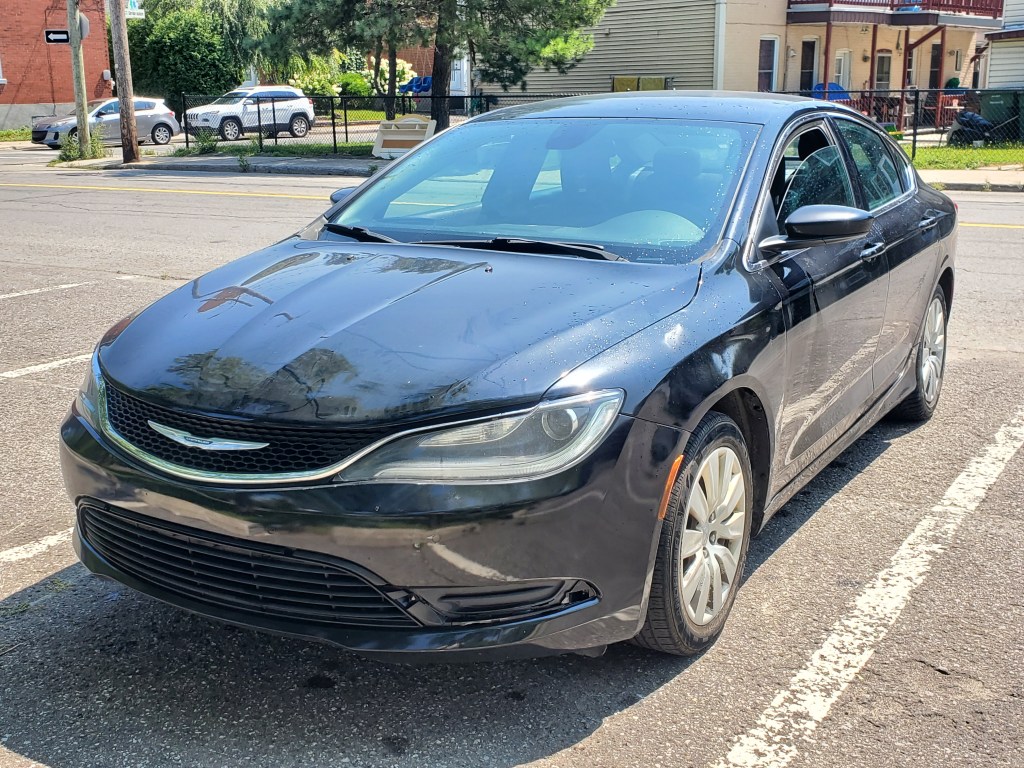 A black Chrysler sedan parked in a lot on a sunny day.